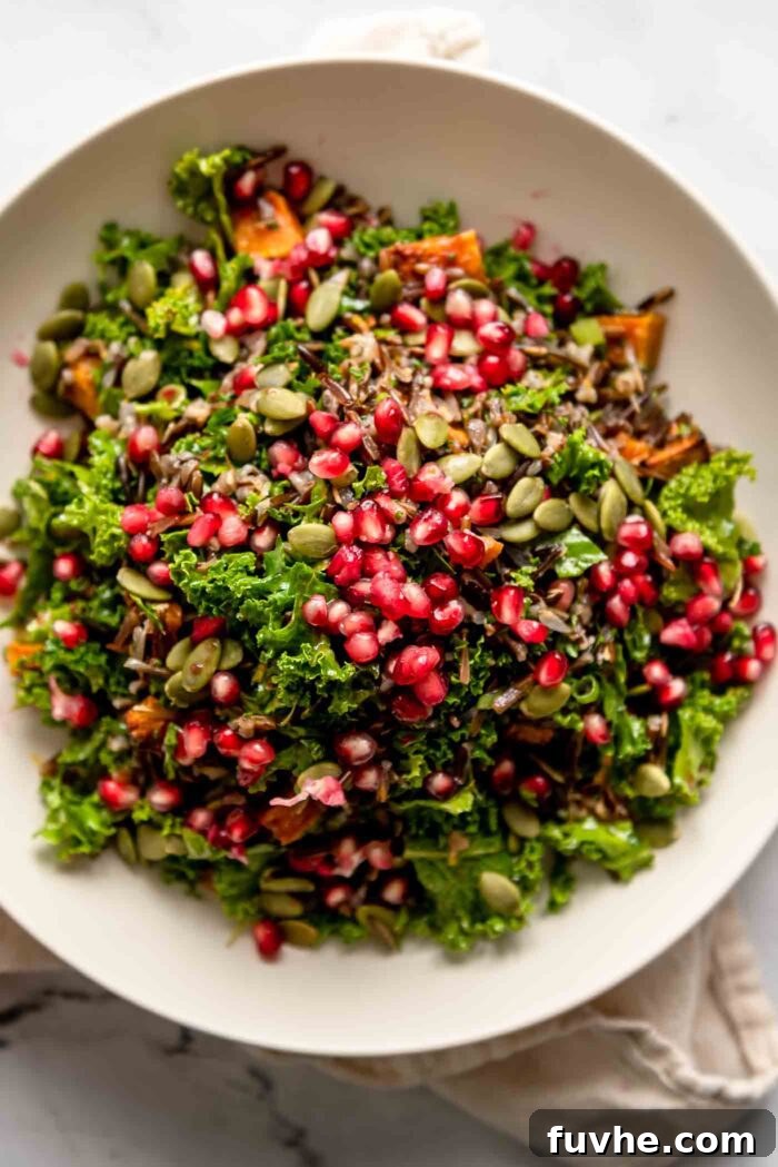 Rustic Wild Rice Salad 8 Overhead view of a holiday-inspired wild rice salad with pomegranate arils, pumpkin seeds, kale and cubes of roasted butternut squash in a bowl, ready to be enjoyed.