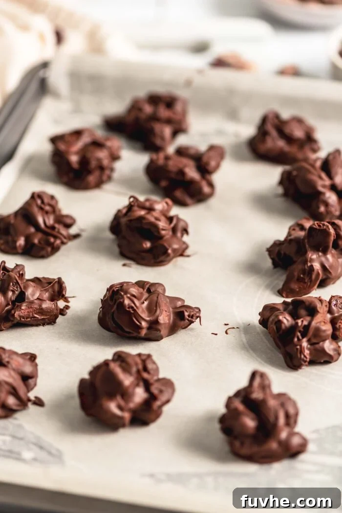 Irresistible Nutty Clusters 7 A baking sheet filled with 14 perfectly set chocolate nut clusters, their surfaces firm and glossy, signifying they are ready to be enjoyed.