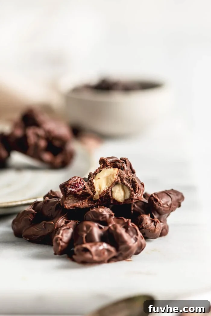 Irresistible Nutty Clusters 8 Close up of a homemade chocolate nut cluster, with a neat bite taken out to reveal the crunchy almonds and rich chocolate interior, highlighting its delicious texture.
