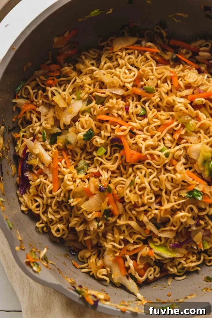 Ramen noodle stir fry with cabbage, carrot and green onion in a skillet.