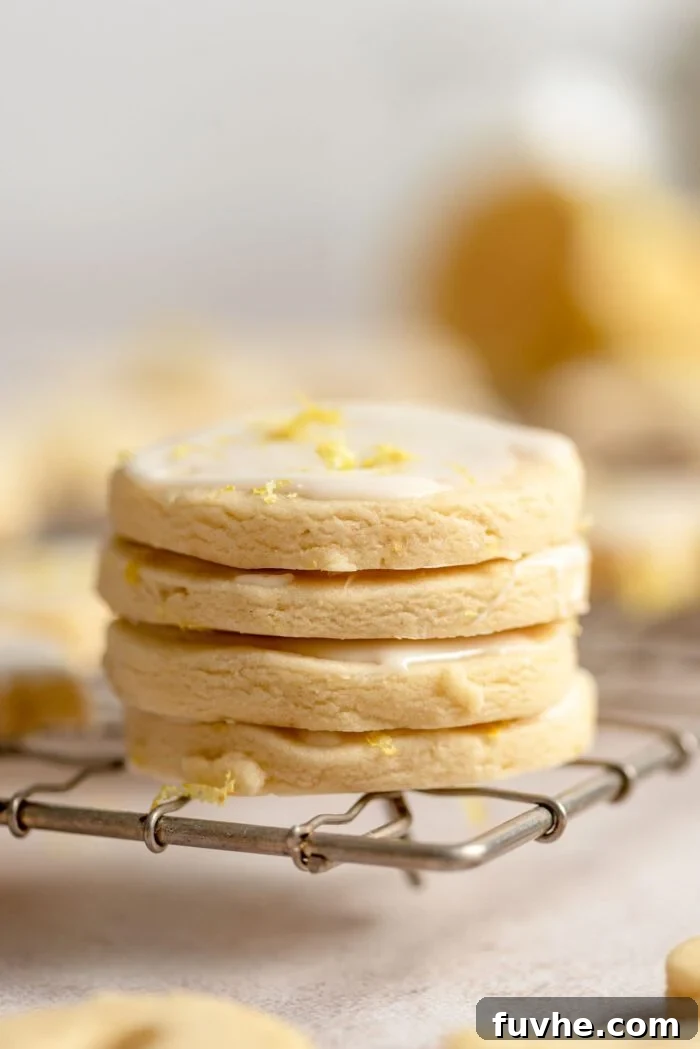 Zesty Lemon Shortbread Bites 11 A stack of 4 small iced lemon shortbread cookies on a cooling rack.