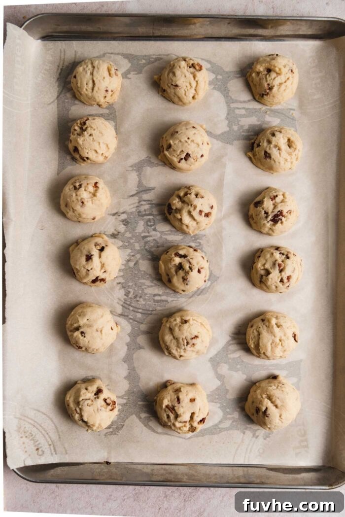 Melt-in-Your-Mouth Vegan Pecan Snowballs 7 18 baked pecan snowball cookies on a baking tray lined with parchment paper.