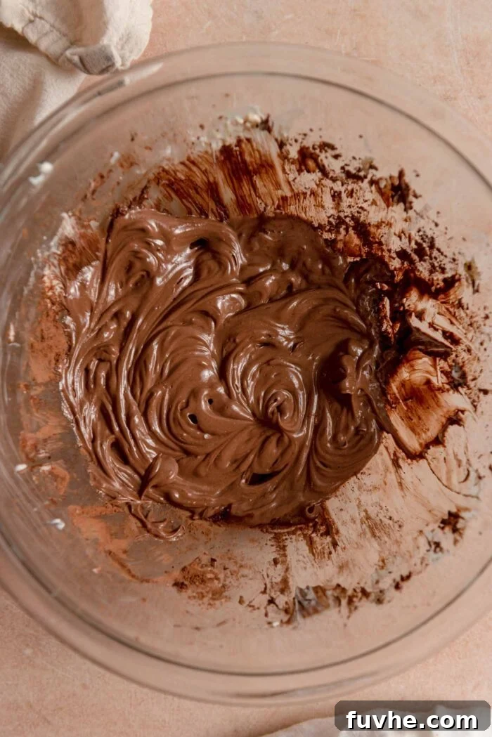 A smooth and creamy melted chocolate mixture in a glass mixing bowl.