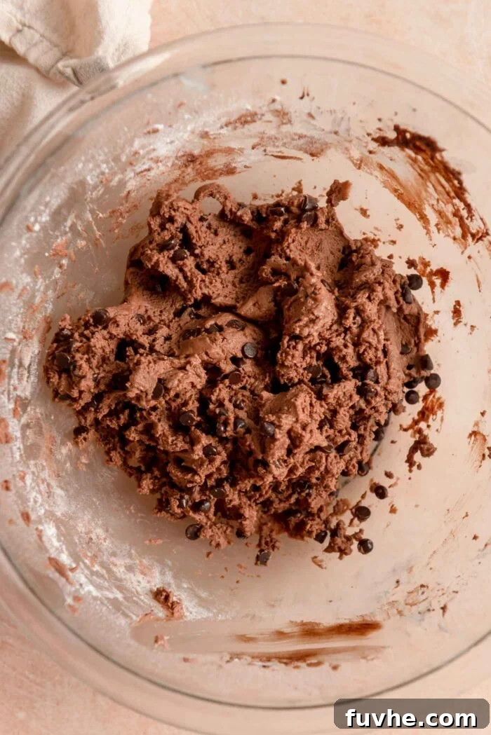 Chocolate chip snowball cookie dough in a glass mixing bowl.