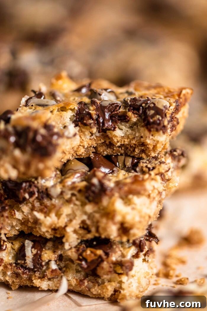 A close-up view of a gooey vegan 7 layer magic bar with a bite taken out, showcasing the rich layers of chocolate chips, pecans, and coconut atop a graham cracker crust.