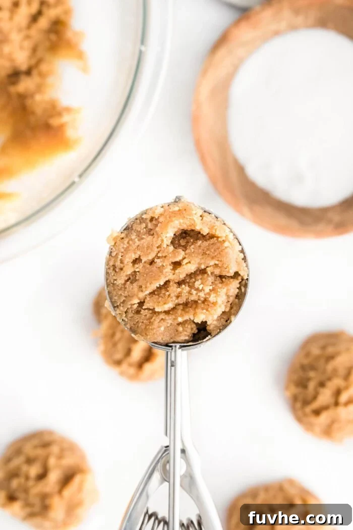 Spoonable Peanut Butter Cookie Dough 6 A small metal cookie scoop perfectly portions a ball of edible peanut butter cookie dough, showing its ideal consistency.