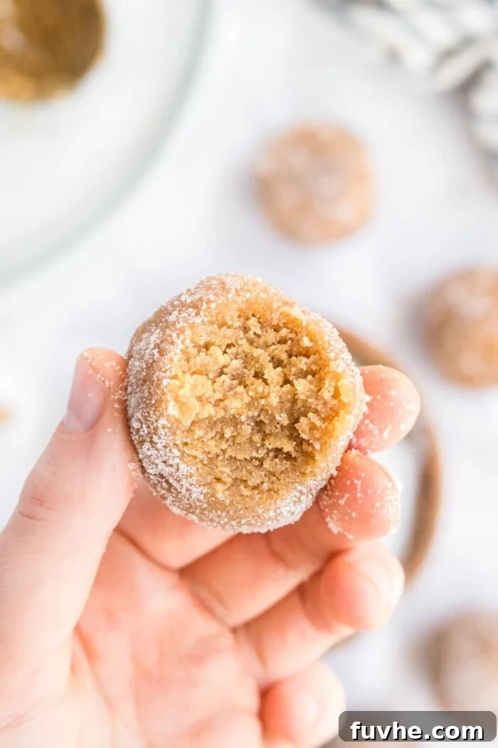 Spoonable Peanut Butter Cookie Dough 8 A hand holds a delicious edible peanut butter cookie dough ball with a bite taken out, showing its soft, irresistible interior.