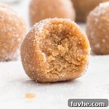 Spoonable Peanut Butter Cookie Dough 9 A perfectly formed ball of edible peanut butter cookie dough, rolled in sugar, with a bite taken out to reveal its soft, chewy interior.