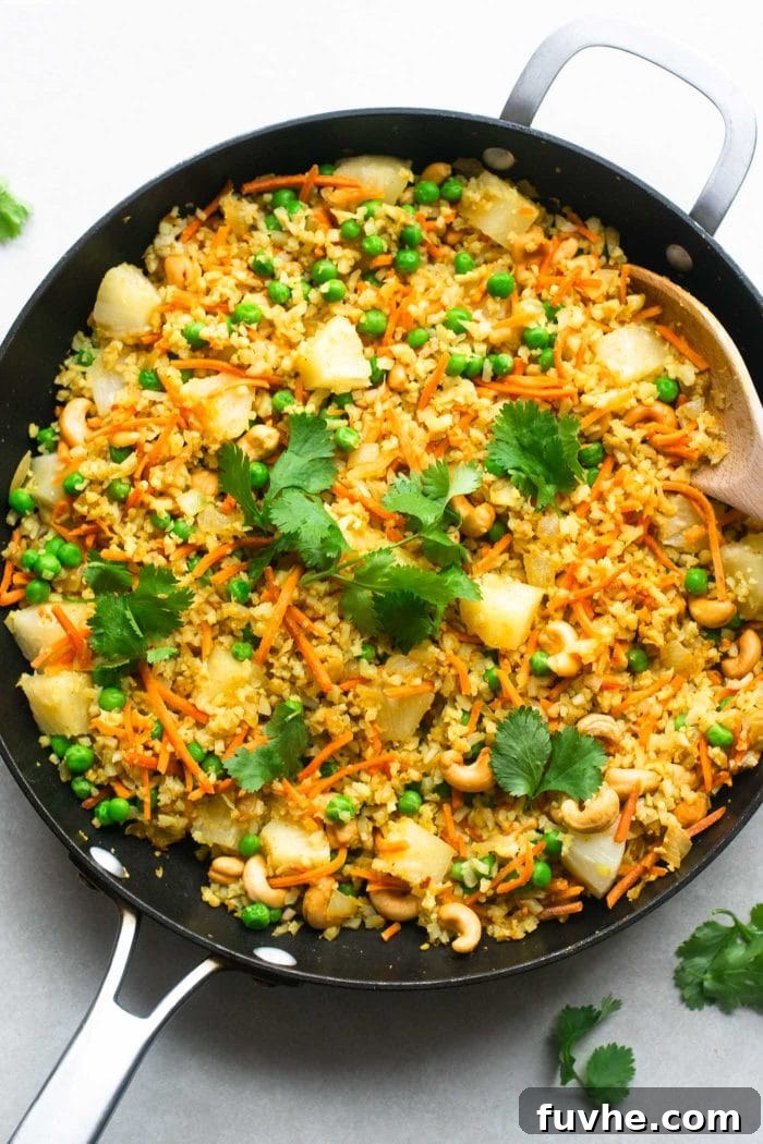 A close-up shot of the finished Vegan Cashew Cauliflower Rice with pineapple, green peas, and fresh cilantro garnish, ready to be enjoyed as a wholesome and flavorful meal.