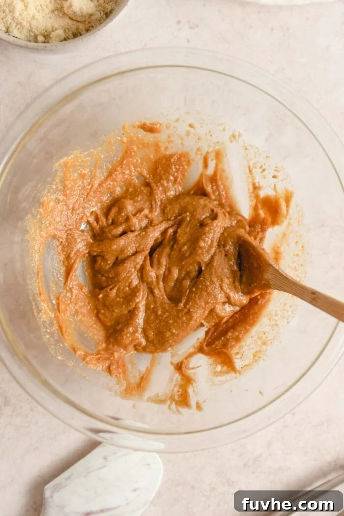 Peanut butter and maple syrup mixed together in a glass mixing bowl.