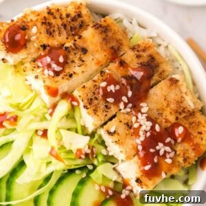 Close up of tofu katsu slices in a bowl with cabbage and cucumber.
