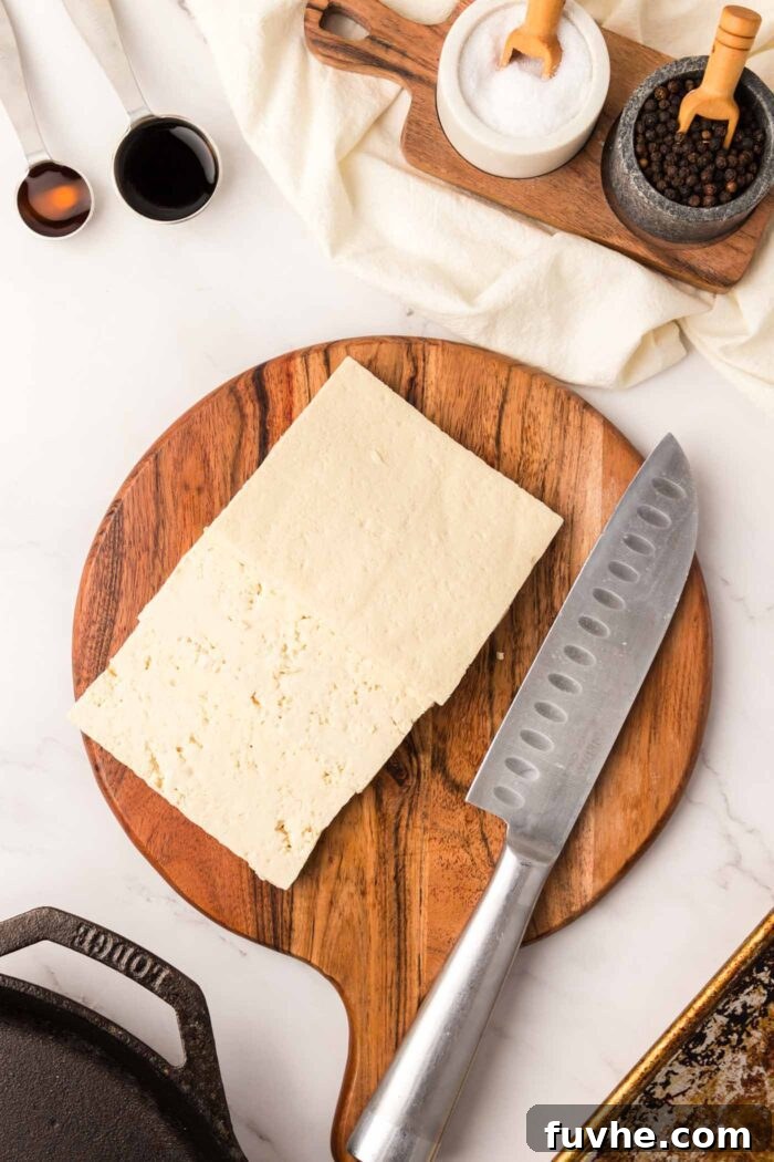 A block of extra-firm tofu neatly sliced into three thin rectangular pieces on a cutting board, ready for pressing.
