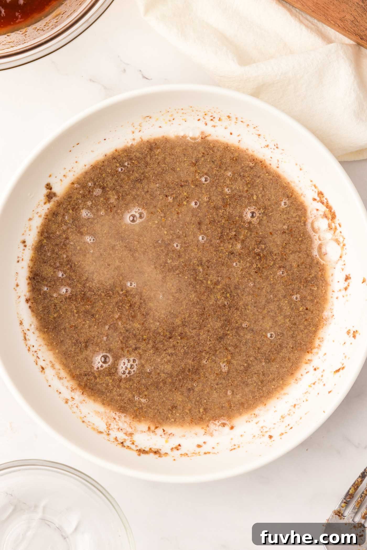 Ground flax meal perfectly mixed with water in a large, shallow bowl, forming the sticky binder for breading.