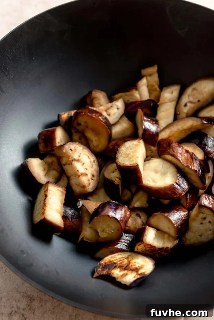 Browned stir fried eggplant cooked in a large wok.