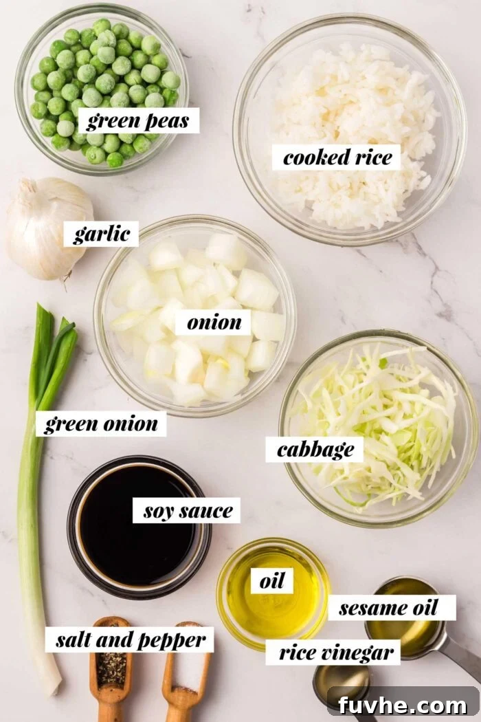 All the fresh and pantry ingredients laid out for preparing a delicious cabbage fried rice recipe, including fresh cabbage, rice, peas, and various sauces.