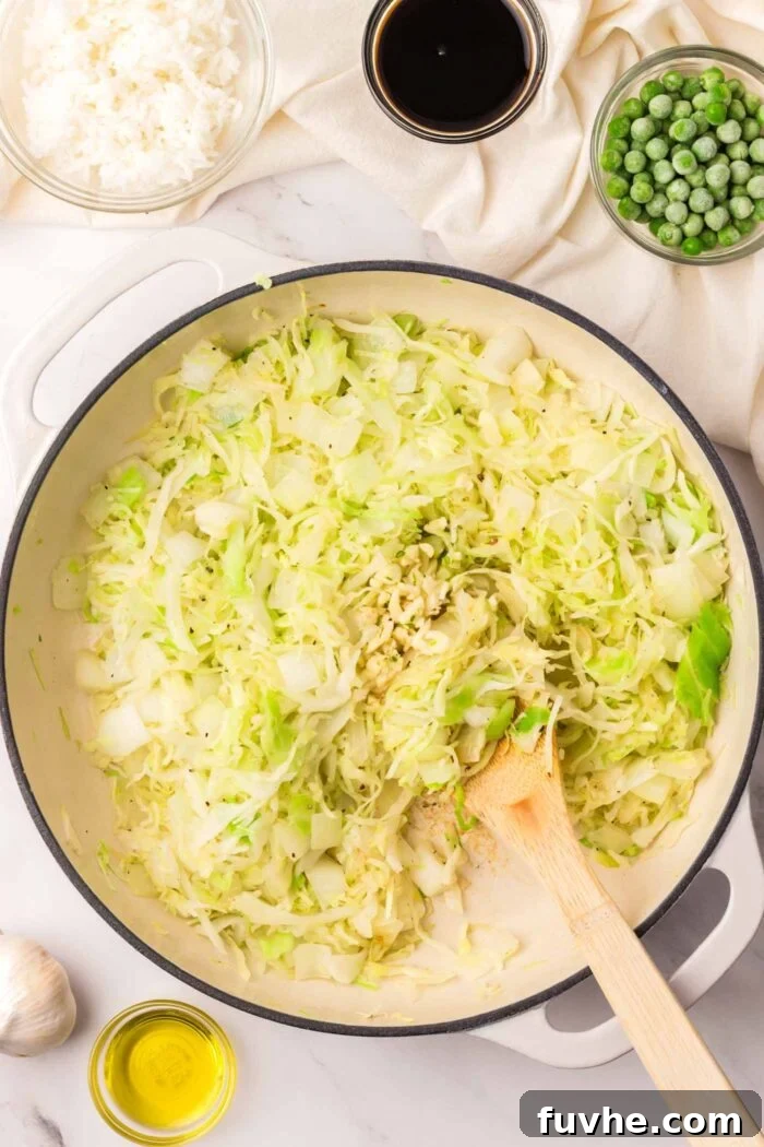Fresh cabbage, diced onion, and minced garlic sizzling in a hot skillet, gently cooking down.