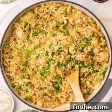 A large skillet of cabbage fried rice with green peas and onion.