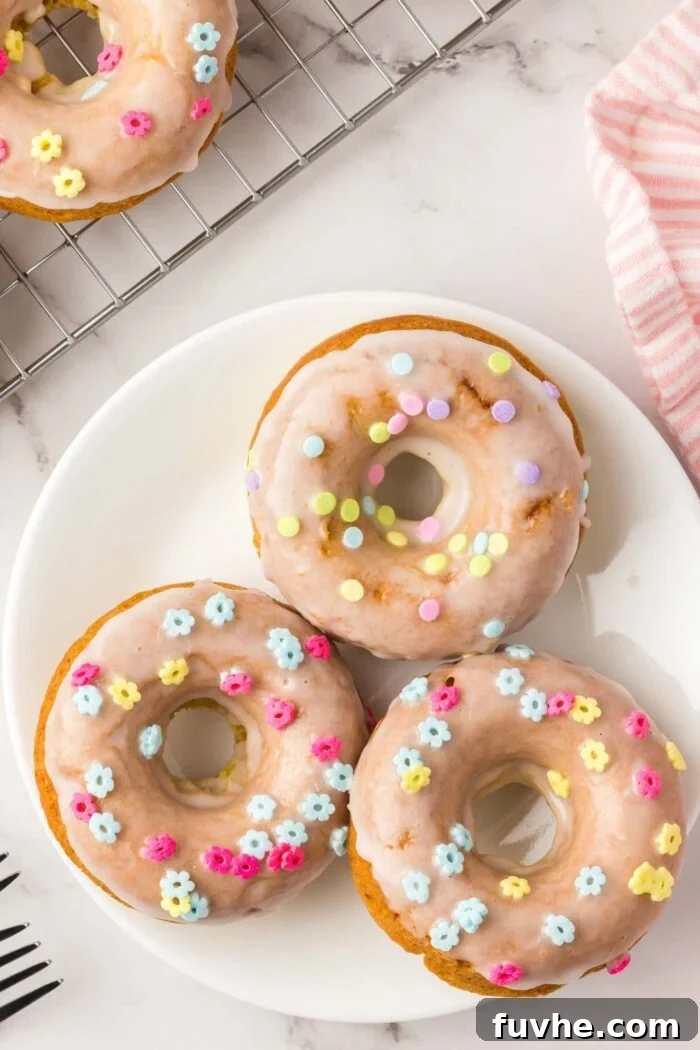 Three glazed donuts with sprinkles on a small plate.