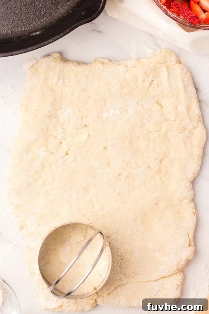 Heavenly Vegan Strawberry Shortcake 11 A round biscuit cutter positioned firmly on a rectangle of prepared biscuit dough, ready to stamp out perfectly shaped biscuits.