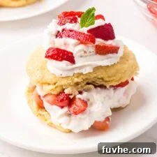 Strawberry shortcakes topped with a small piece of mint on small round plates.