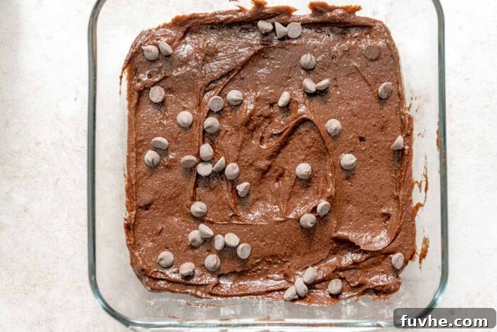 Decadent Vegan Avocado Brownies 7 Raw brownie batter topped with chocolate chips in a glass baking dish.