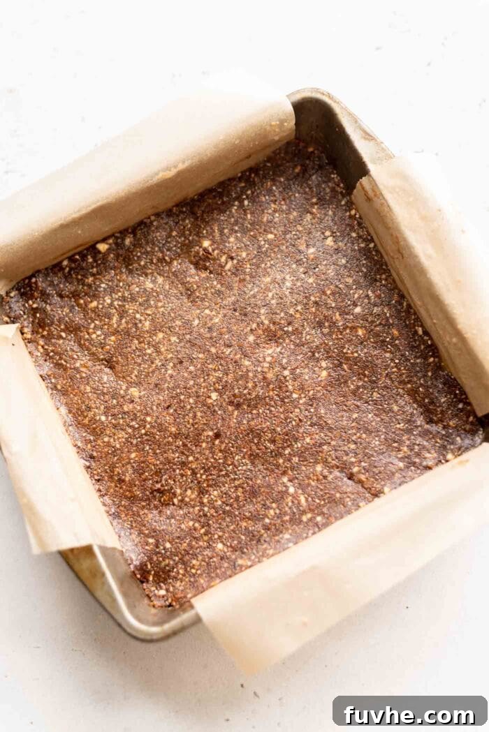 A square baking pan filled with the pressed chocolate energy bar dough, ready for the next step.