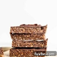 A stack of 4 large no-bake chocolate energy bars sitting on parchment paper, ready to be enjoyed.