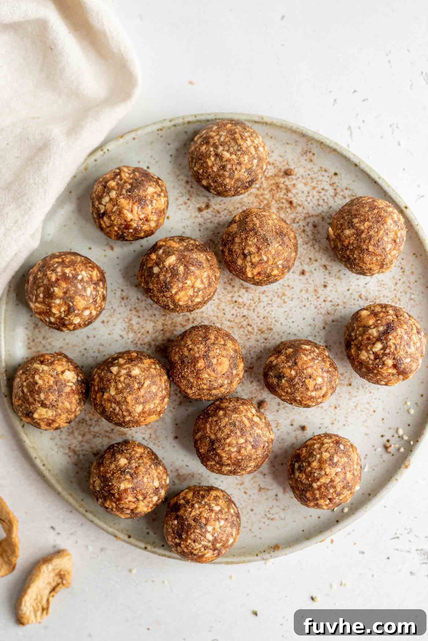A plate of apple energy balls, showcasing their perfectly rolled, golden-brown appearance, ready to be enjoyed as a healthy and delicious snack.