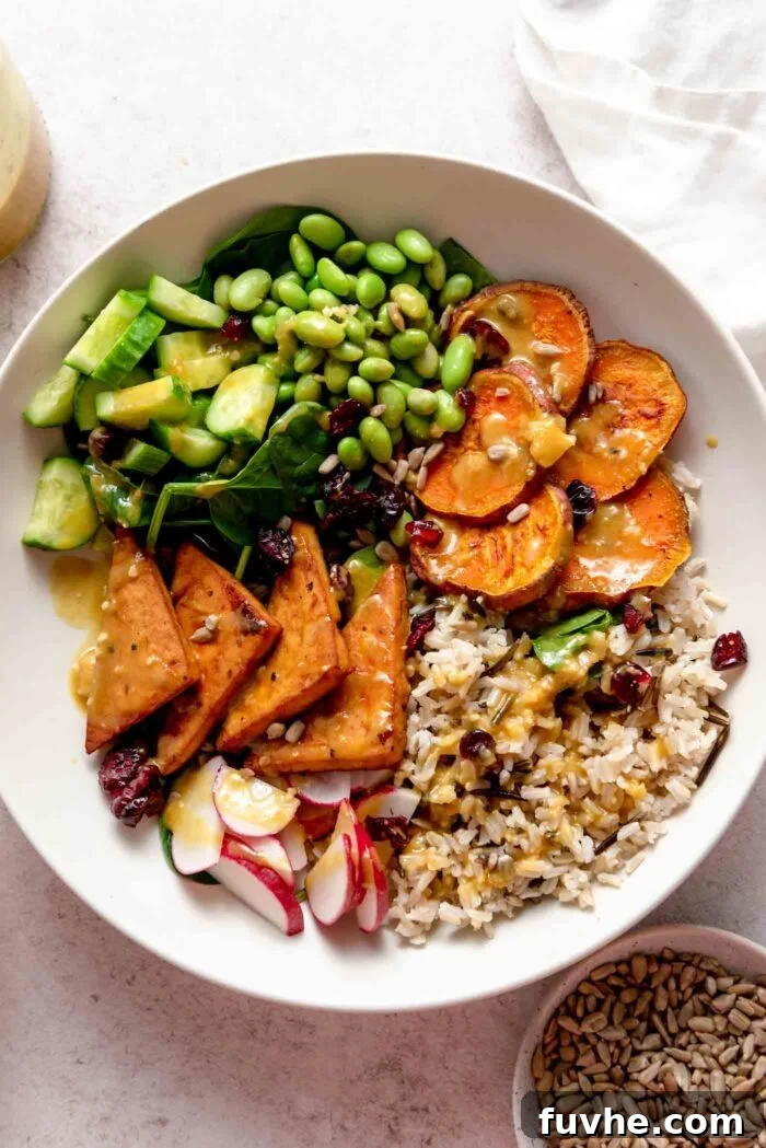Overhead view of a vegetarian veggie power bowl with sweet potato, tofu, radish, cucumber, edamame and rice.