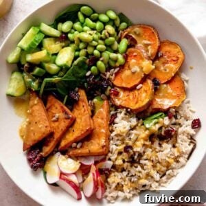 Overhead view of a vegetarian veggie power bowl with sweet potato, tofu, radish, cucumber, edamame and rice.