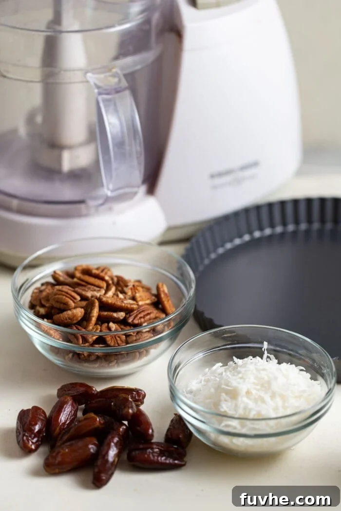Three clear glass containers holding the essential raw ingredients: soft pitted dates, unsweetened shredded coconut, and whole raw pecans, neatly separated and ready for preparation.