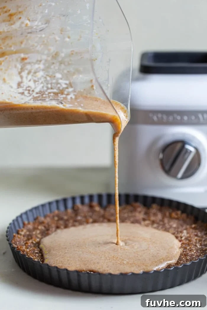 The smooth, creamy no-bake pie filling being poured artfully over the pre-pressed crust in a pie dish, preparing for its final chill.
