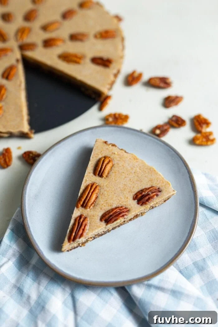 A delectable slice of raw maple pecan pie presented on a small blue plate, highlighting its smooth filling and rustic crust.