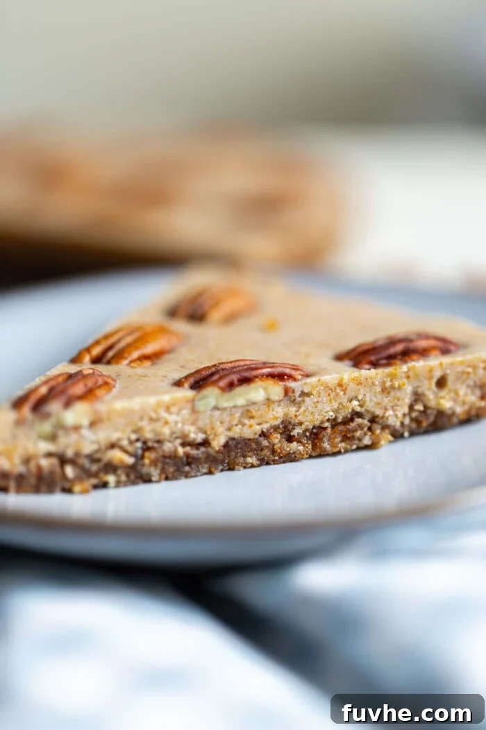 Another inviting shot of a single slice of raw maple pecan pie, perfectly poised on a small blue plate, emphasizing its rich texture and natural allure.