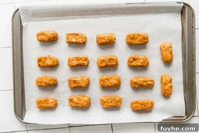 18 small butterfinger candy bars on a baking sheet before they've been coated in melted chocolate.