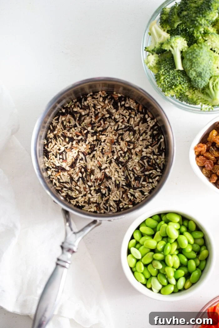 Cooked wild rice in a pot with bowl of edamame and broccoli beside it.
