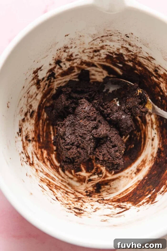 Chocolate fudge dough mixed together in a large glass mixing bowl.