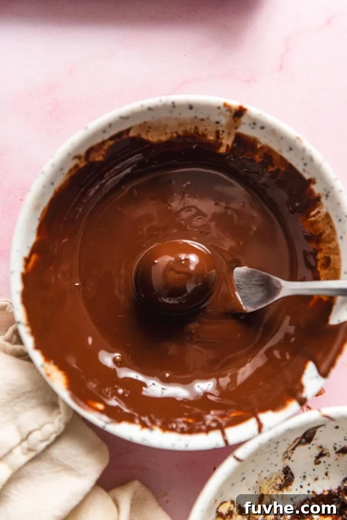 Fork dipping a truffle in melted chocolate in a small bowl.