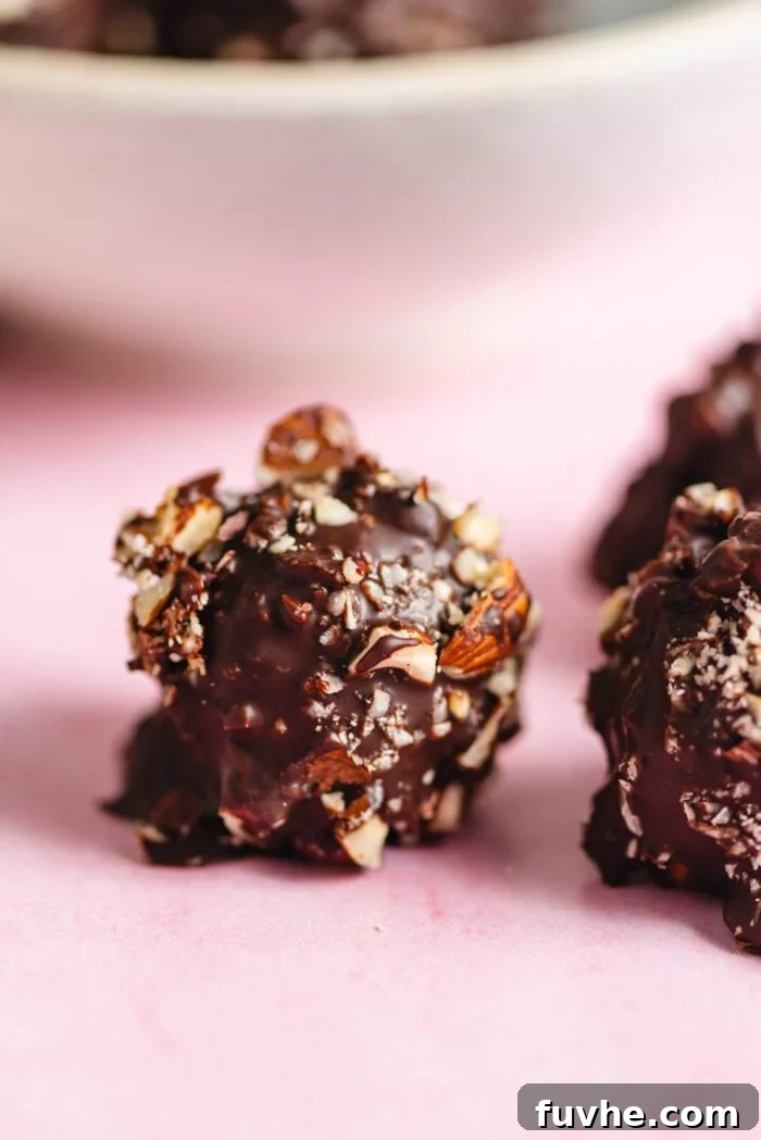 A homemade Ferrero Rocher sitting on a pink marble surface with a few more candies just out of the frame.