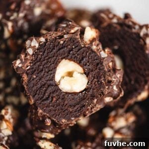 A homemade Ferrero Rocher truffle sliced in half so you can see the texture of the fudge and hazelnut in the middle.