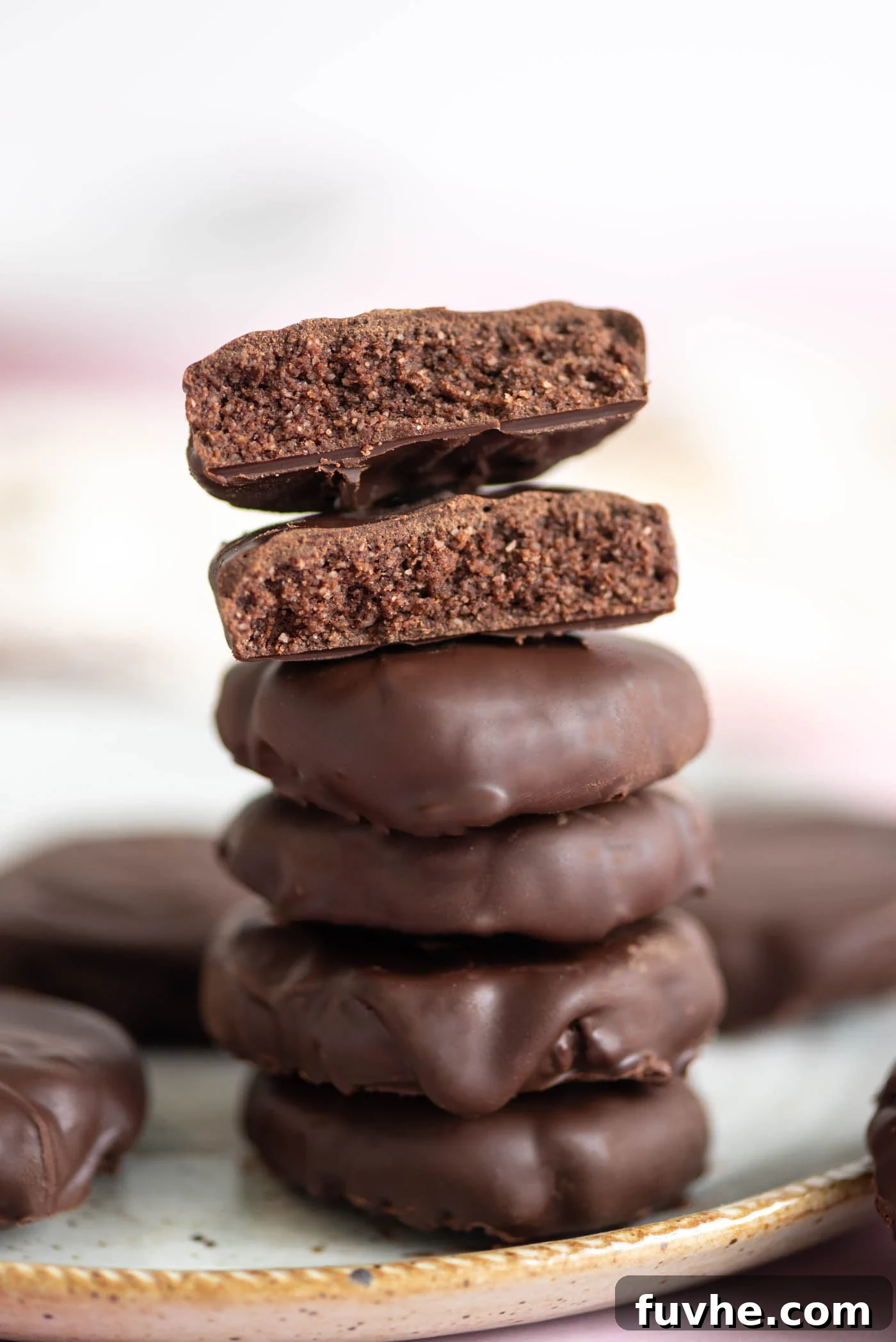 Stack of 4 Thin Mint cookies with one on top broken in half and stacked so you can see the texture inside the cookie, showcasing the crisp texture of this homemade vegan Thin Mints recipe.