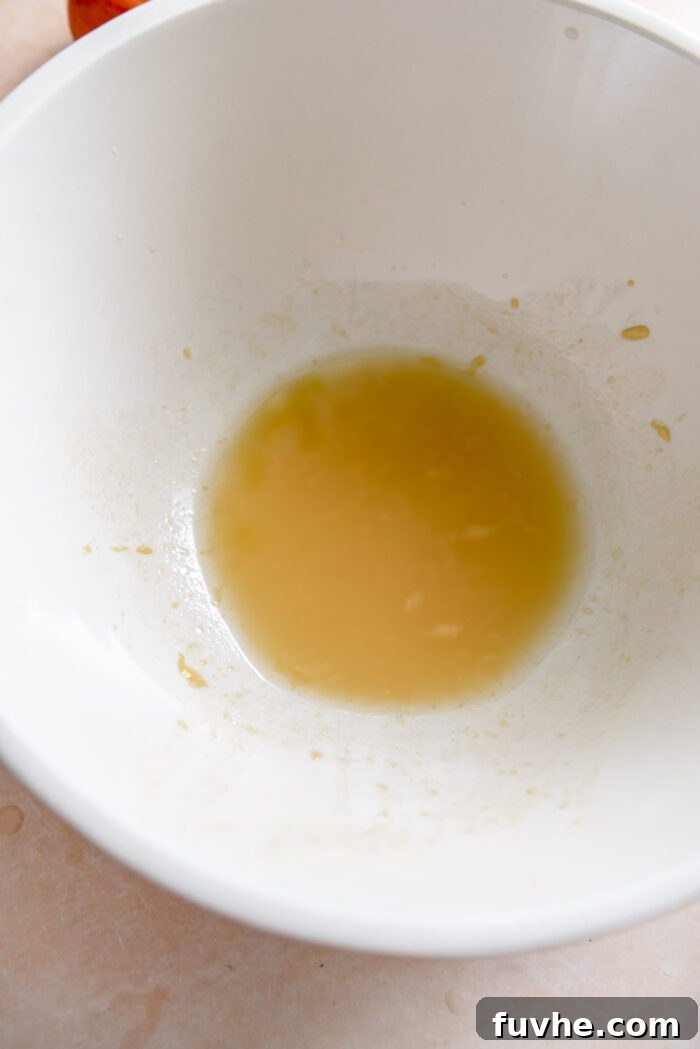 A small amount of a vinaigrette salad dressing in a large mixing bowl.