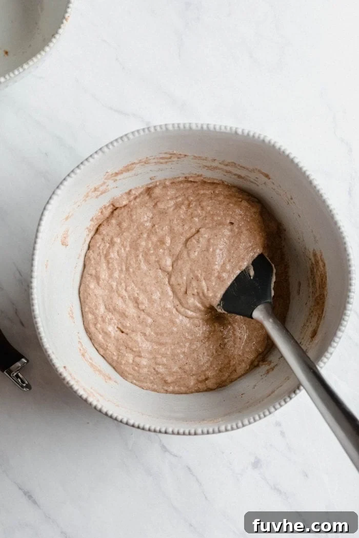 A mixing bowl holding a rich, creamy peanut butter banana pancake batter, showcasing its thick consistency and readiness for cooking, hinting at the fluffy pancakes to come.
