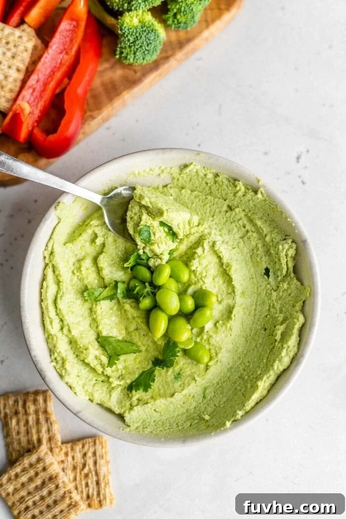 A bowl of edamame hummus topped with edamame beans and cilantro, ready to be enjoyed.