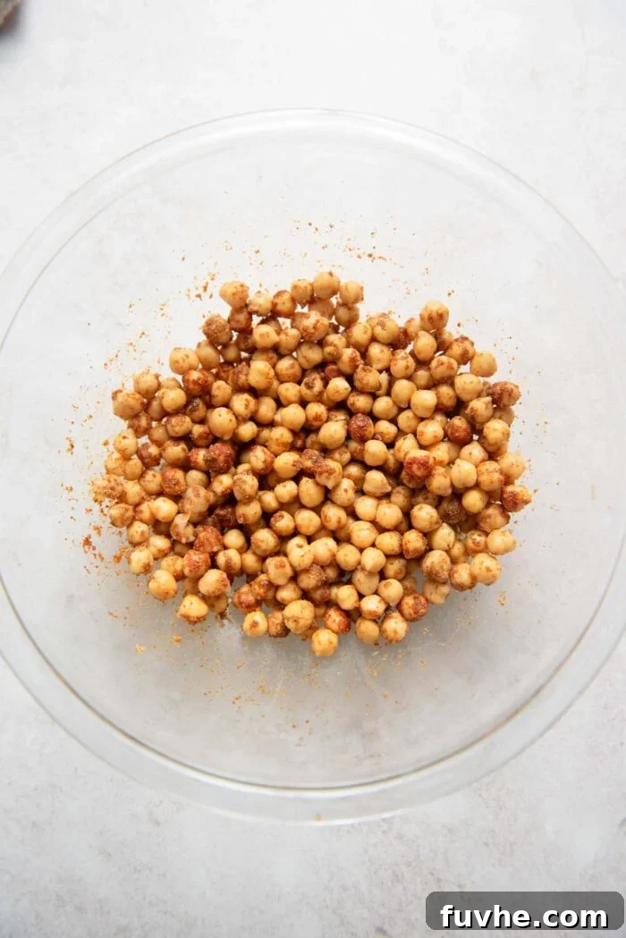 Bowl of chickpeas being mixed with a variety of Mediterranean spices and olive oil.