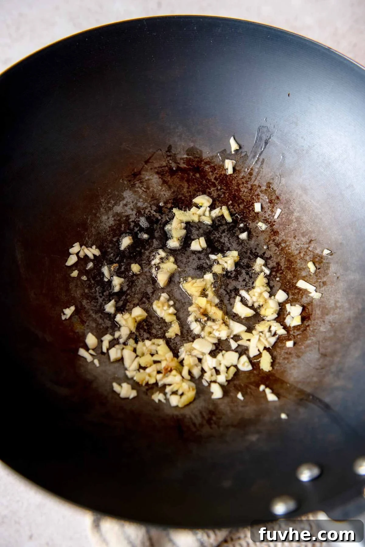 Minced garlic and grated ginger sizzling in toasted sesame oil in a hot wok, filling the kitchen with aromatic scents.