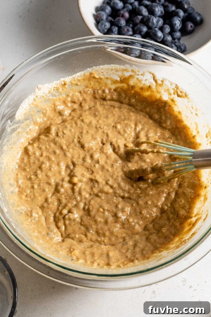 Raw muffin batter in a mixing bowl with a whisk.
