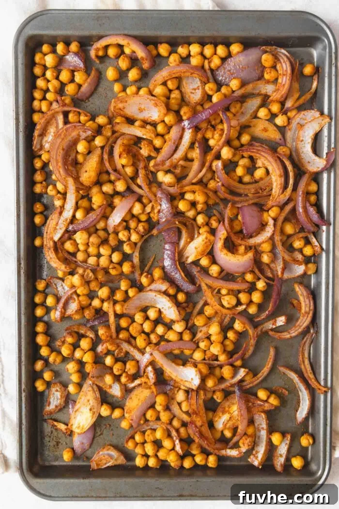 Easy Sheet Pan Sweet Potato Meal 5 Chickpeas and red onion in spices on a baking sheet.