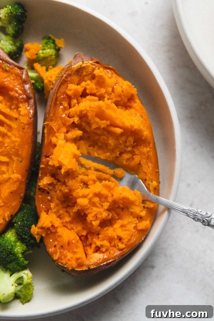 Easy Sheet Pan Sweet Potato Meal 8 Roasted sweet potato half being mashed with a fork on a plate.