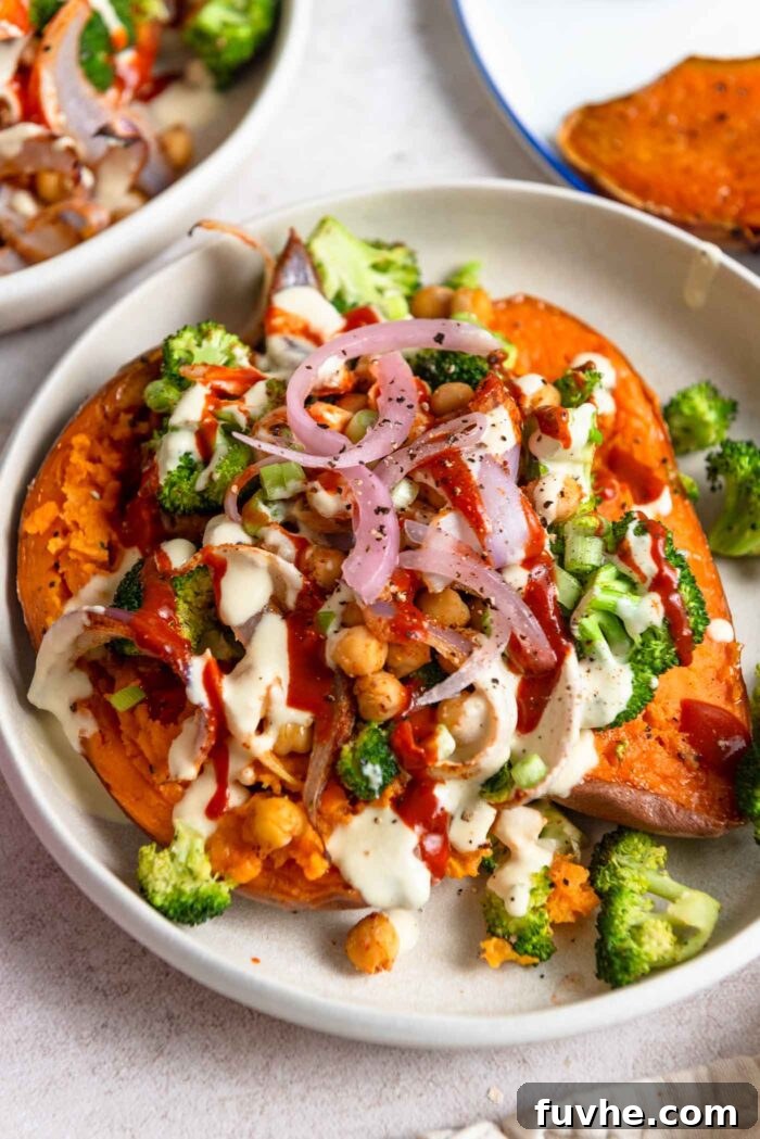 Easy Sheet Pan Sweet Potato Meal 9 Two halves of a sweet potato topped with broccoli, chickpeas, red onion and tahini sauce.
